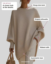 Helene poncho showing its snug crew neck, draped silhouette, ribbed cuffs and asymmetric hem.